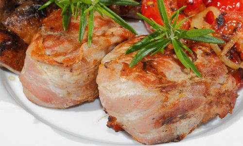 Gegrillte Schweinemedaillons mit Champignons, Paprika, Tomaten auf einem Teller