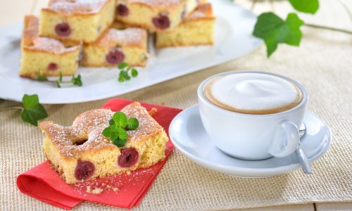 Frisch gebackener Kirschkuchen ( Blechkuchen mit versunkenen Kirschen ) mit einer Tasse Cappuccino - Freshly baked cherry cake with a cup of cappucino